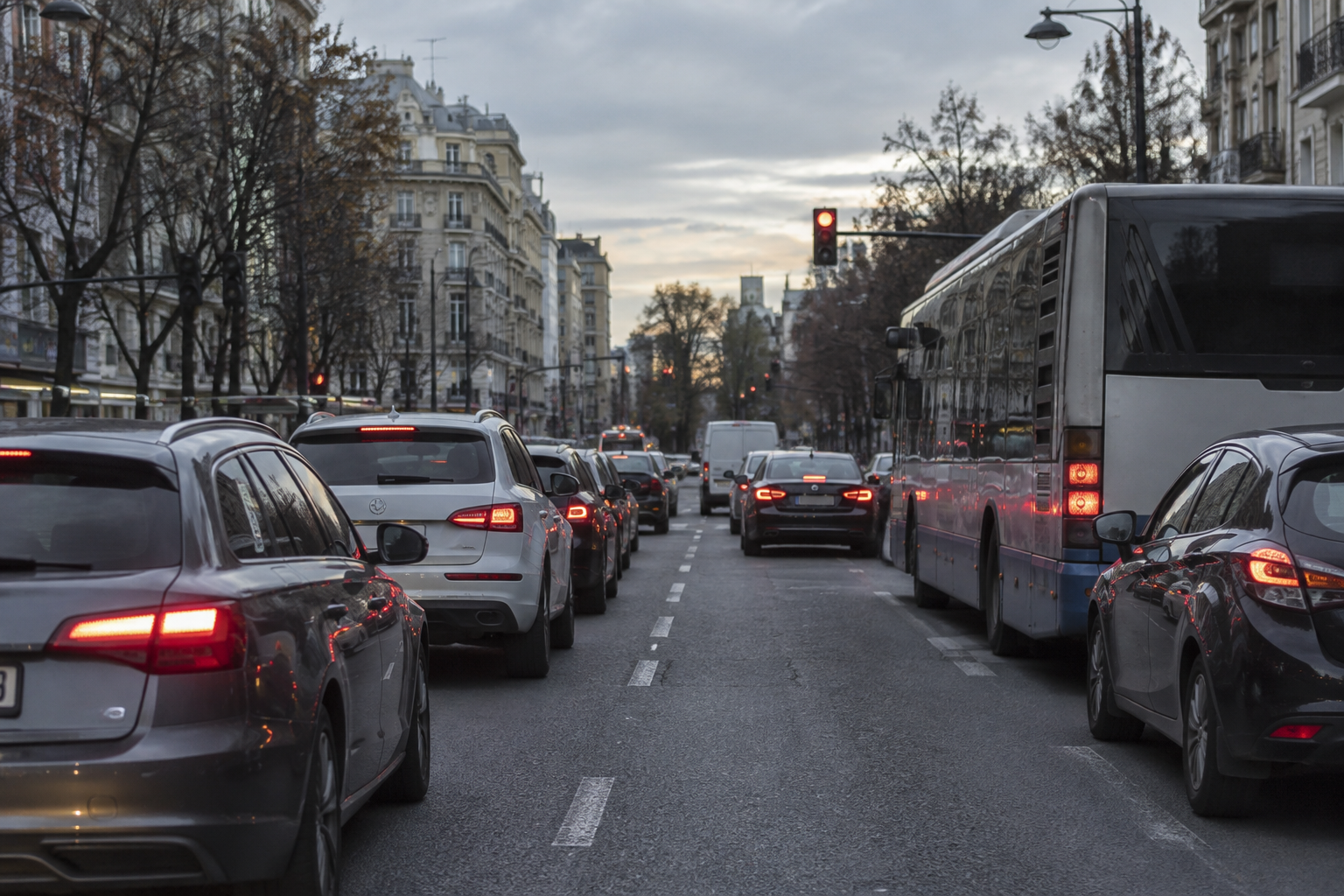 Avenida urbana con tráfico denso y coches en cola que ilustran conducción en ciudad.